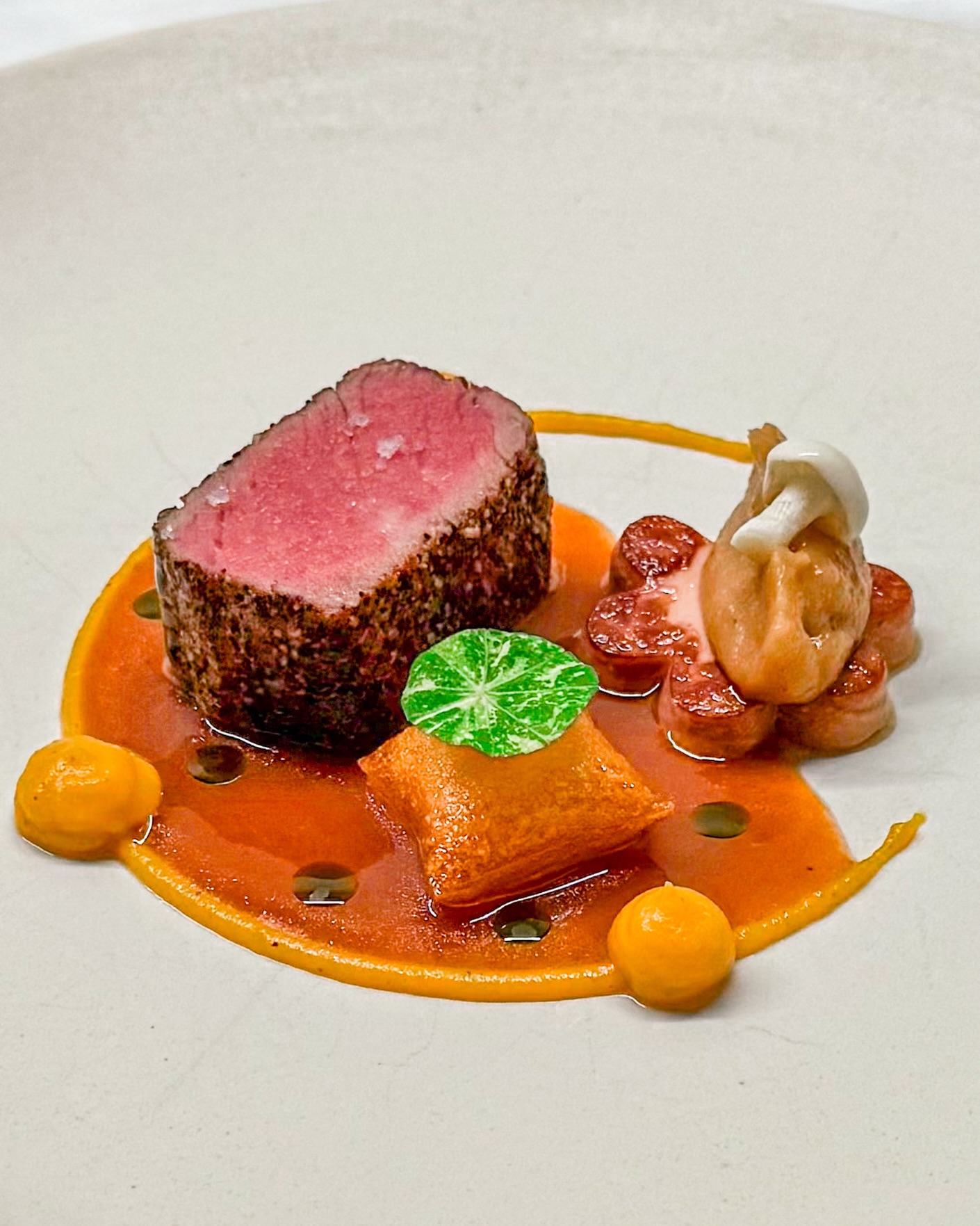 🥩🎃 Ossenhaas • Pompoen • Roscoff ui
🇬🇧🥩 Beef tenderloin • Pumpkin • Roscoff onion

Alles komt bij elkaar in dit gerechtje. Een heerlijk mals stukje ossenhaas, gebakken ganzenlever en crème van Roscoff ui vormen een heerlijke combinatie 🧅 

Daarbij zie je rondom een kruidige crème van pompoen met vadouvan. En een lekker knapperige pomme soufflé, dit keer in een vierkante vorm 🥔 

Een zoetzuur beukenzwammetje en een lekkere portsaus maken dit gerechtje compleet, samen met een paar druppels kruidenolie en een blaadje Oost-Indische kers 🌿 

✌️