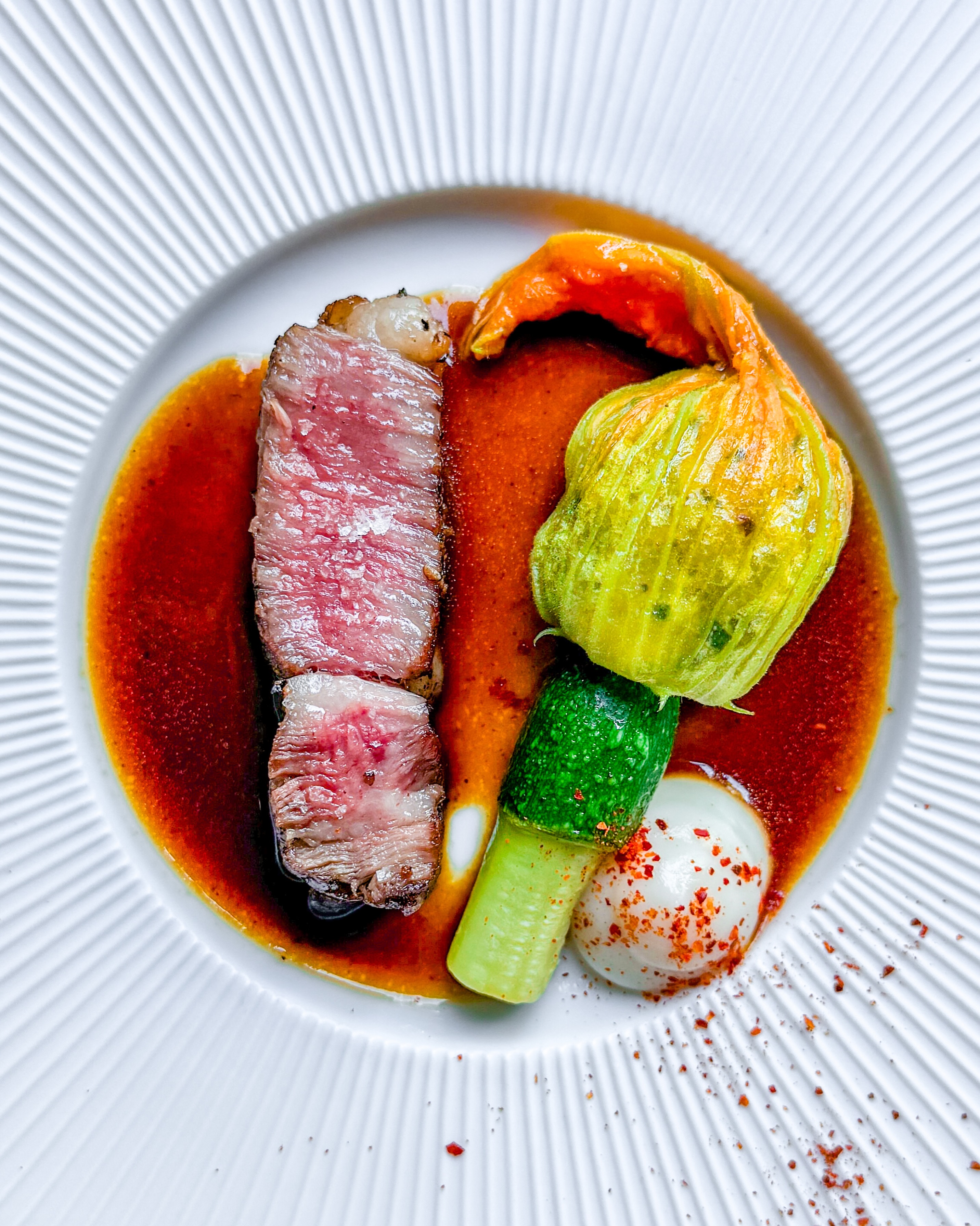 🥩 Wagyu ribeye • Courgettebloem • Knolselderij🇬🇧 Wagyu ribeye • Courgette flower • CeleriacZó’n mooi stukje vlees, Wagyu A5 ribeye. Prachtig gemarmerd en fantastisch mals. Zacht gegaard op 50°C, een beetje grof zeezout erop en klaar ben je.Ernaast ligt een gevulde courgettebloem (met fijngesneden courgette en o.a. citroentijm) voor een frisse touch. De dot knolselderij brengt wat romigs in het gerecht. Om tegen het vlees op te boksen maakte ik een volle jus van de afsnijdsels. Alles bij elkaar een mooi gebalanceerd gerecht.✌️ #steak #wagyu #courgette #finediningathome