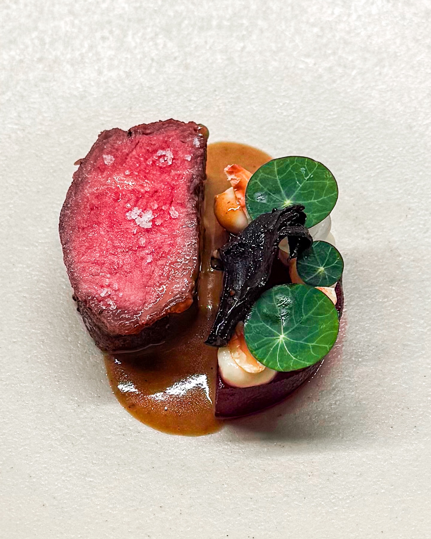 🥩🫜 Dry aged entrecote • Rode biet • Aardpeer
🇬🇧🥩 Dry aged sirloin • Beetroot • Sunchoke

Het is zó leuk om verschillende smaken samen te brengen. Ik zoek naar een overeenkomst en combineer op basis daarvan. Voor dit gerechtje haakte ik aan op de aarde smaken van aardpeer, rode biet en paddenstoelen 🍄‍🟫 

Je ziet een lekker stukje dry aged entrecote met ernaast een halve plak gepofte rode biet. Op die biet ligt zoetzure aardpeer, crème van aardpeer met miso, geroosterde hazelnoten en zilveruitjes 🧅 

Hierop zie je gebakken trompettes de la mort. De romige saus is op basis van eekhoorntjesbrood. Een paar uitgestoken blaadjes Oost-Indische kers maken dit gerechtje af 🌿 

✌️